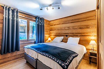 A bedroom with wood paneling and a bed with a blue blanket on it