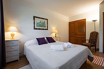 A bedroom with a large bed and a chair