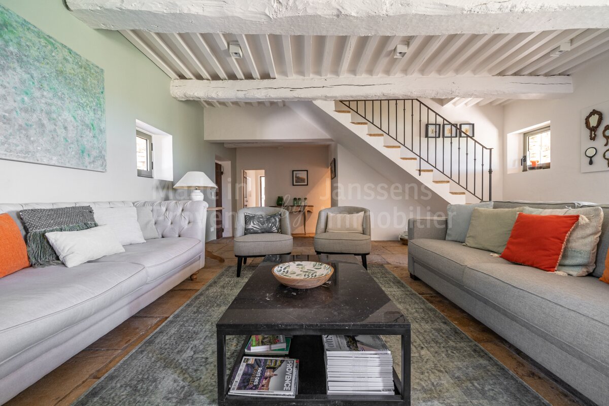 A living room with a staircase and a couch that says anssens immobilier