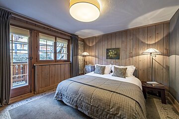 A bedroom with a painting on the wall above the bed