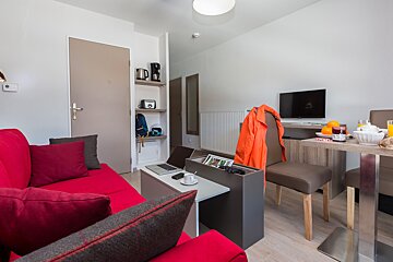 A living room with a red couch and a tv