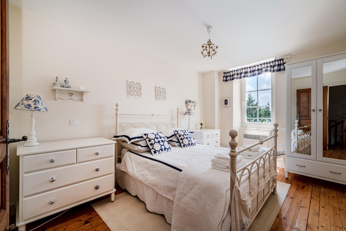 A bedroom with a white bed and white dresser