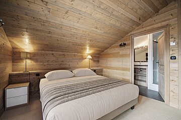 A bedroom with a wooden ceiling and a bed