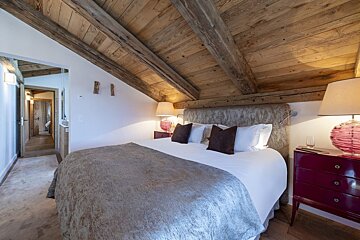 A bedroom with a wooden ceiling and a bed