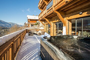 A hot tub sits on the deck of a wooden house