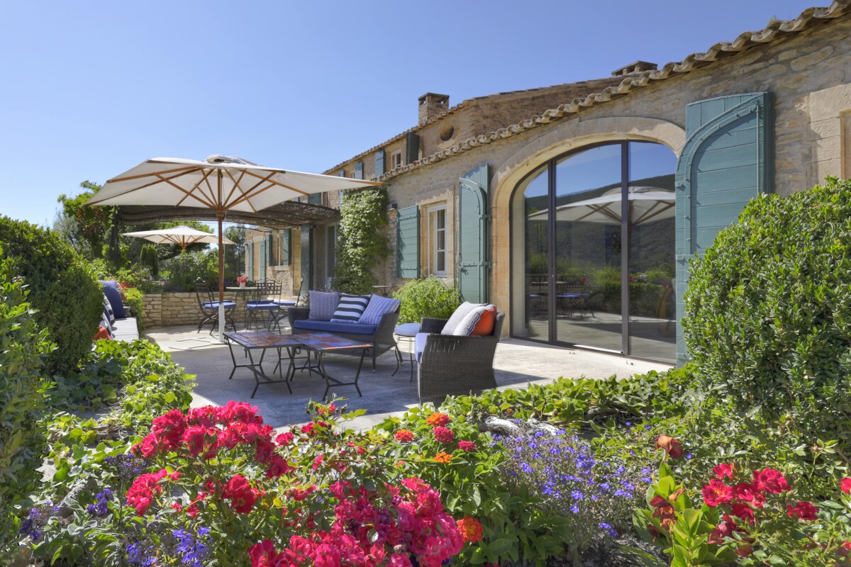 A patio with a couch and umbrellas in front of a house