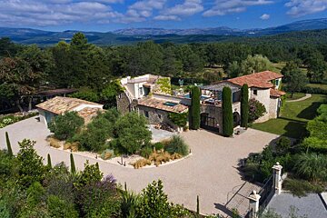 An aerial view of a large house with mountains in the background