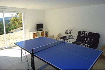 A ping pong table in a room with a couch that says east east