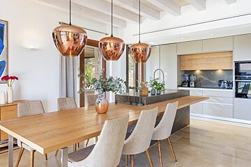 A dining room with a wooden table and chairs and copper pendant lights