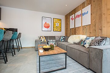 A living room with a couch and a table with a poster on the wall that says tour de france