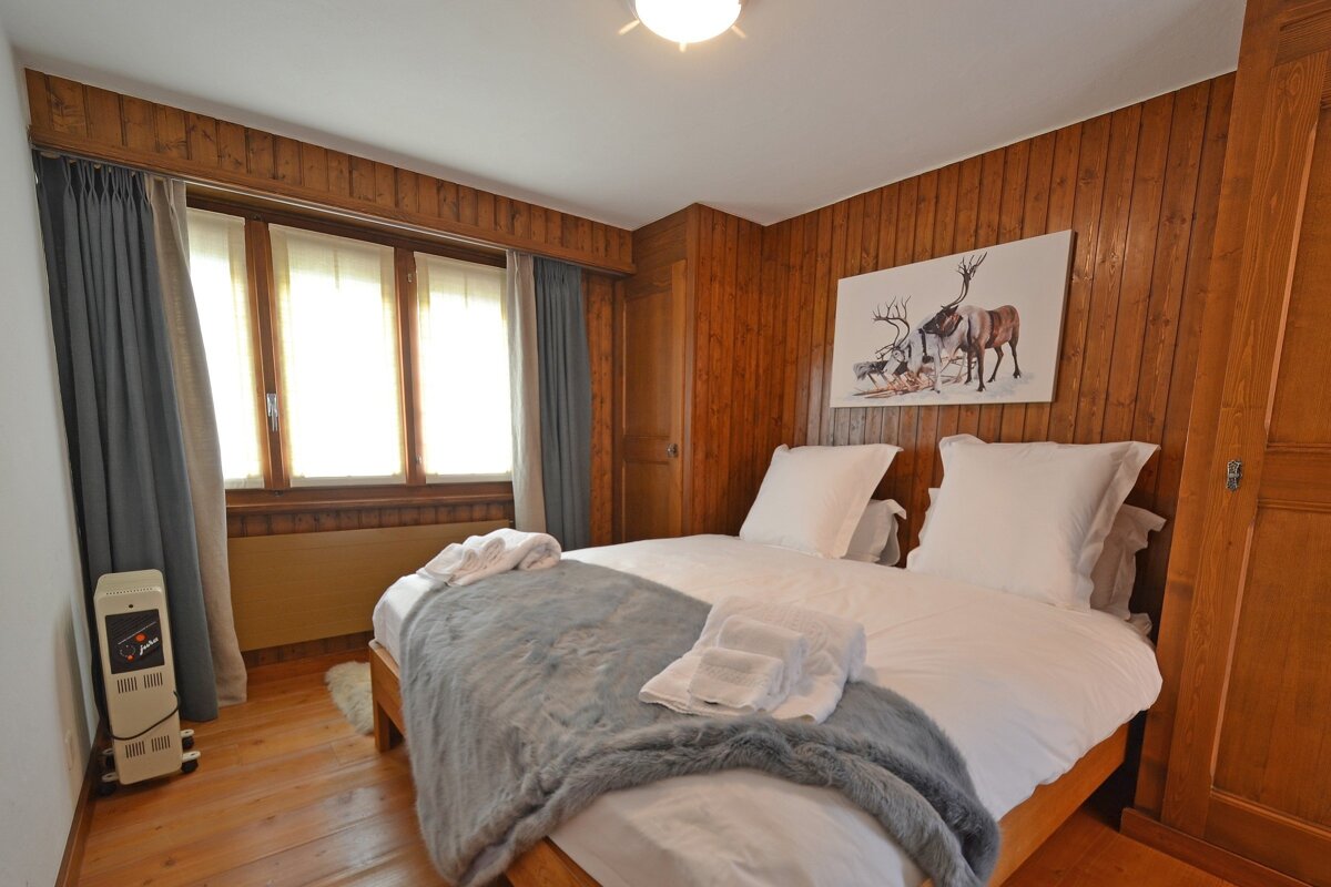 A bedroom with a deer painting on the wall above the bed