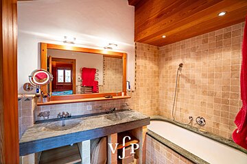 A bathroom with a bathtub and a sink with the letter v on the bottom