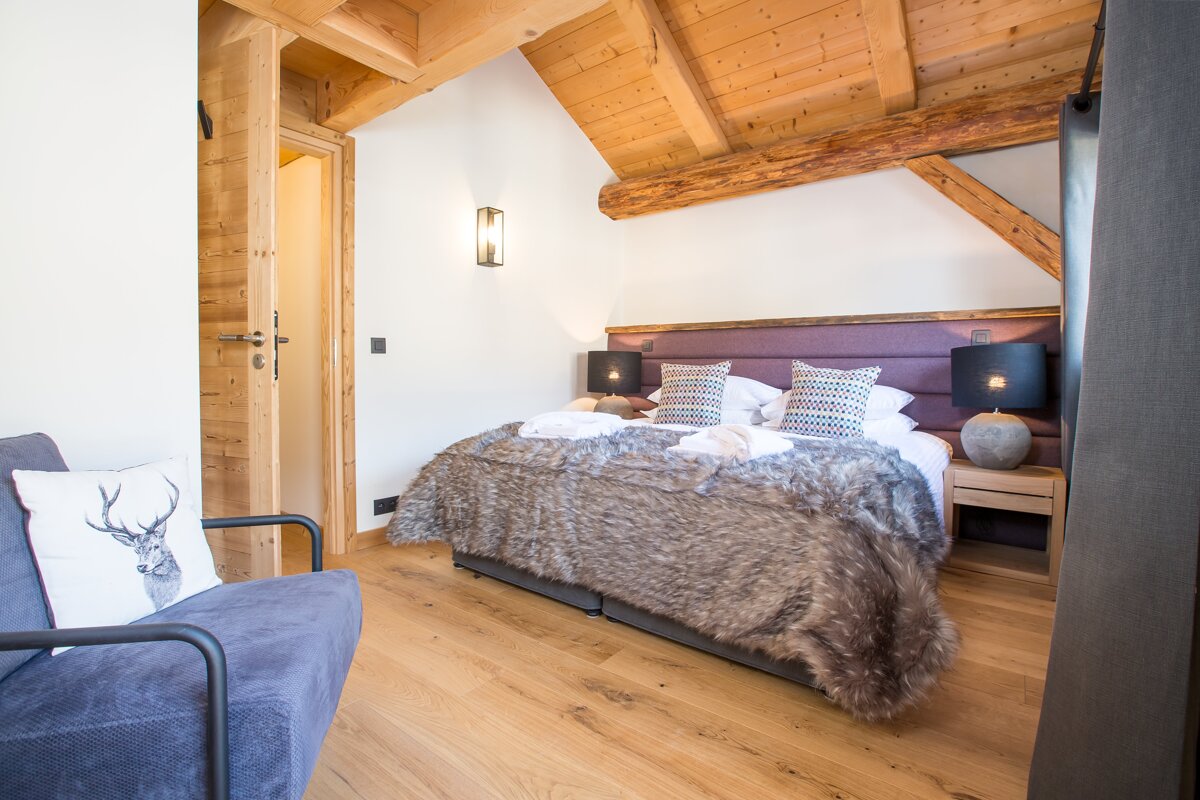 A bedroom with a bed and a chair with a deer pillow