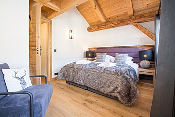 A bedroom with a bed and a chair with a deer pillow