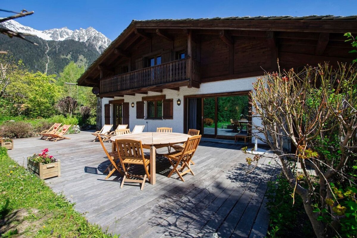 A wooden deck with a table and chairs in front of a house