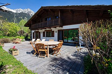 A wooden deck with a table and chairs in front of a house
