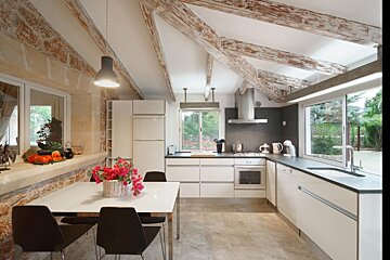 A kitchen with white cabinets and black chairs