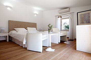 A bedroom with a bed two chairs and a lamp