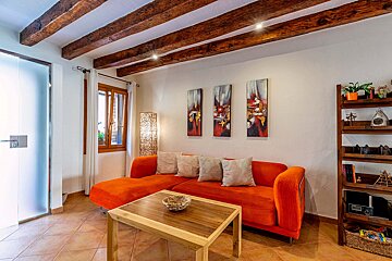 A living room with an orange couch and three paintings on the wall