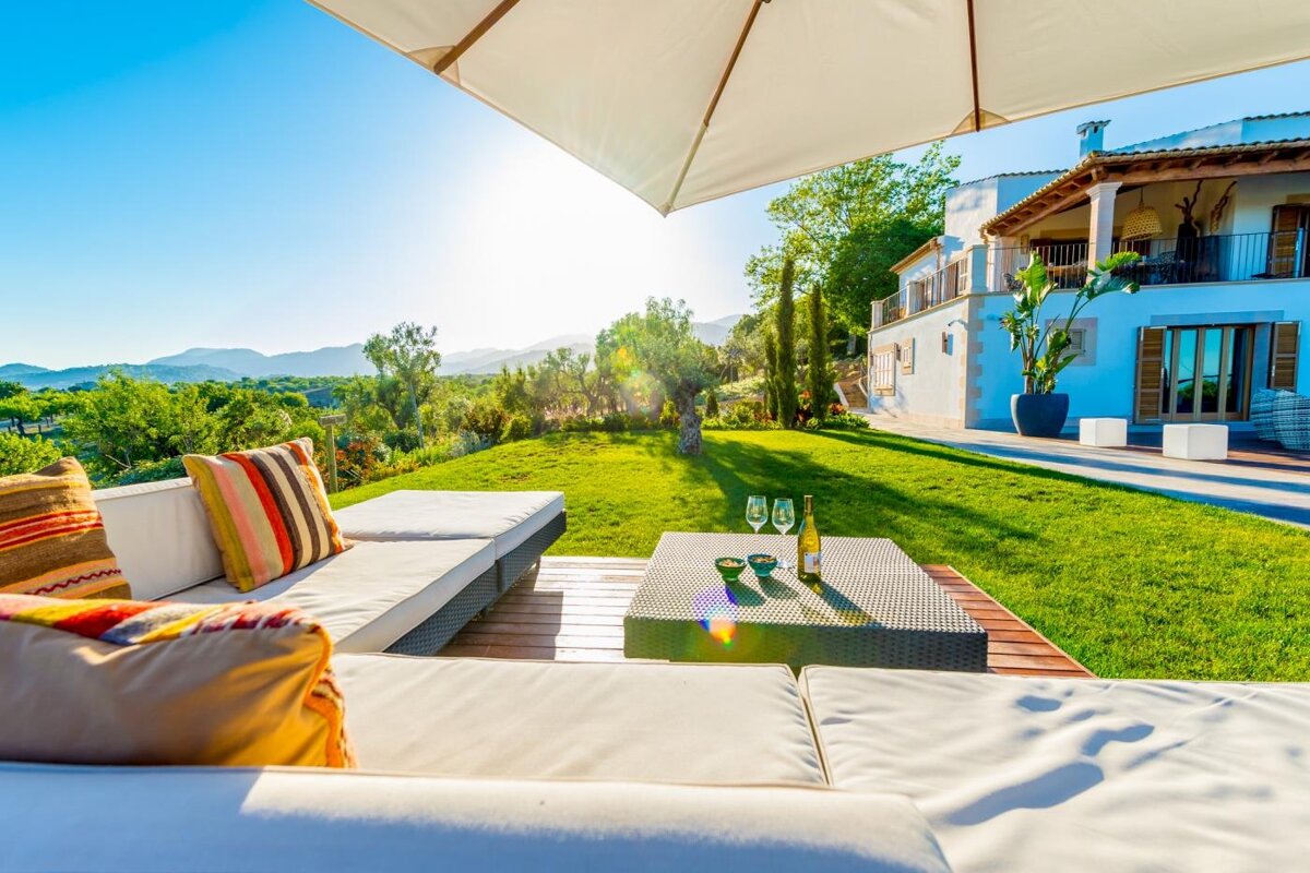 Two glasses of wine sit on a table in the backyard of a house
