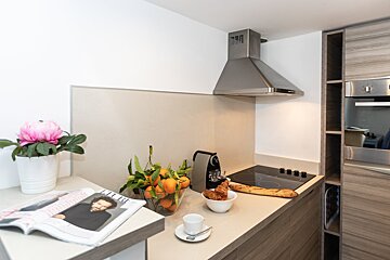 A kitchen counter with a magazine and a bowl of oranges