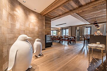 Two white penguin statues are in a hallway leading to a dining room