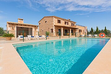 A large swimming pool in front of a stone house
