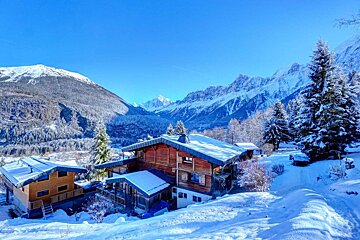 A snowy mountain landscape with a house in the foreground