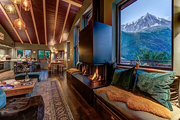 A living room with a fireplace and mountains in the background