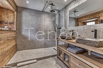 A bathroom with two sinks and a shower with the word ten8o on the wall