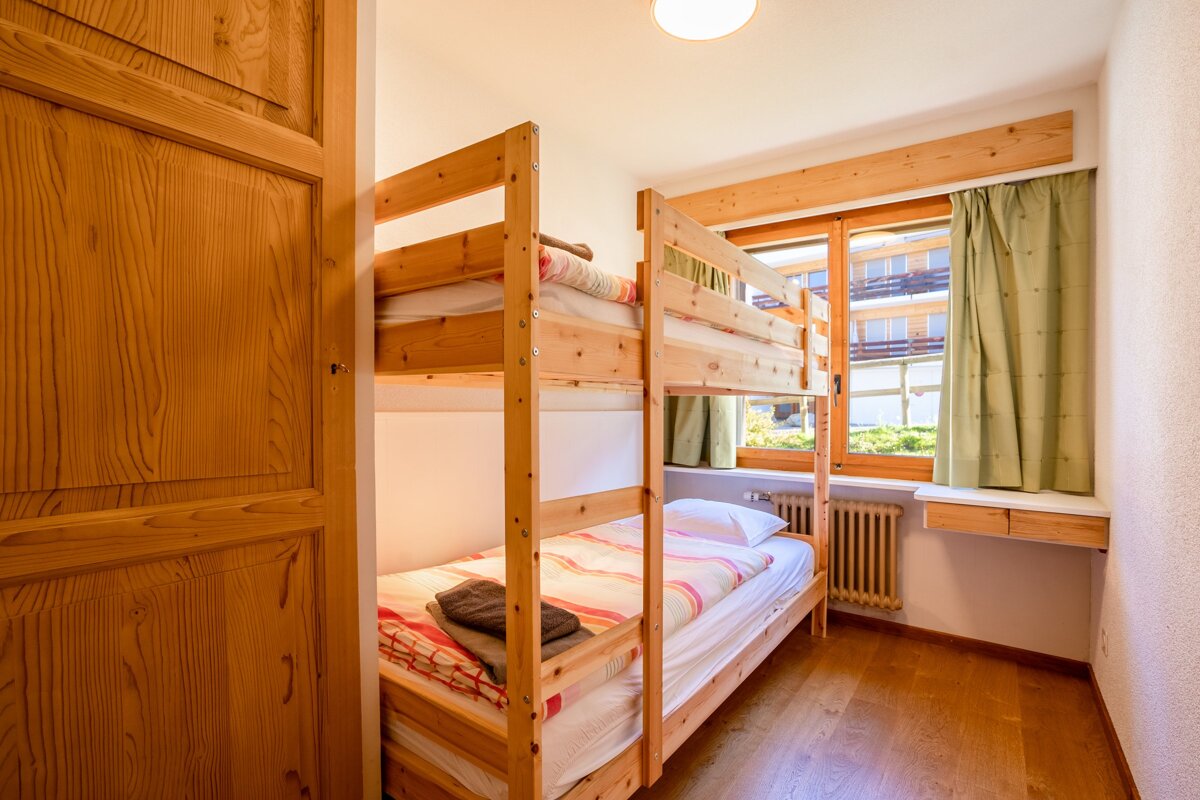 A bunk bed in a bedroom with a window