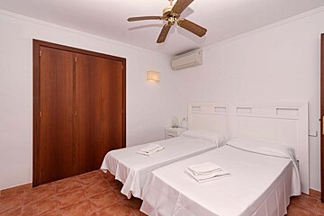 A bedroom with two beds and a ceiling fan