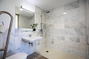 A bathroom with white tiles and a sink and toilet