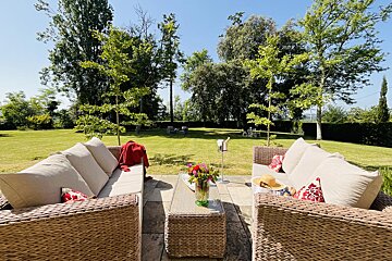 A patio with wicker furniture and a table with a vase of flowers on it