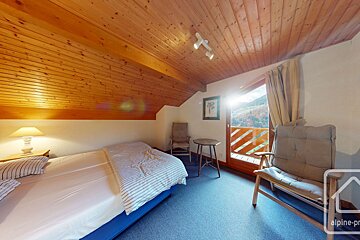 A bedroom with a single bed and a chair and a sign that says alpine-pro