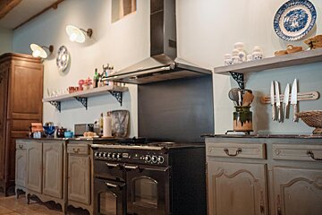 A kitchen with a black stove and a blue and white plate on the wall