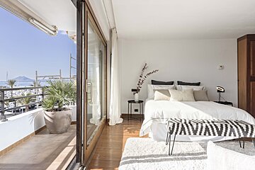 A bedroom with a sliding glass door leading to a balcony overlooking the ocean