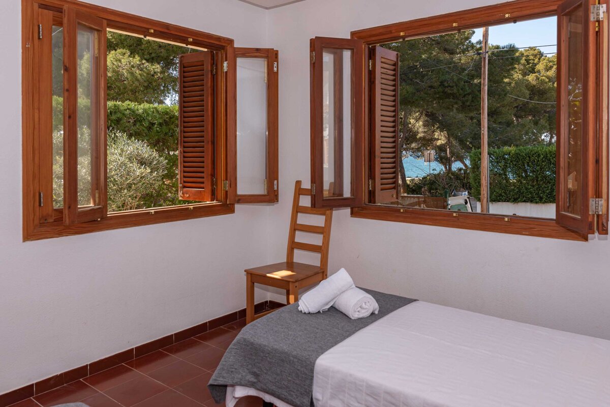 A bedroom with a bed and two windows with wooden shutters
