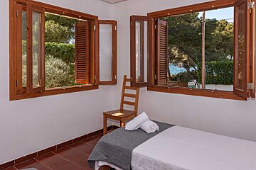A bedroom with a bed and two windows with wooden shutters