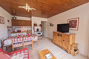 A living room with a table and chairs and a flat screen tv