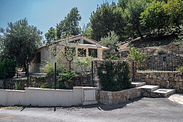 A small house sits on top of a hill surrounded by trees
