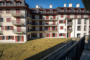 A row of apartment buildings with balconies and red shutters