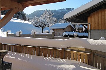 A snowy landscape with a wooden fence in the foreground