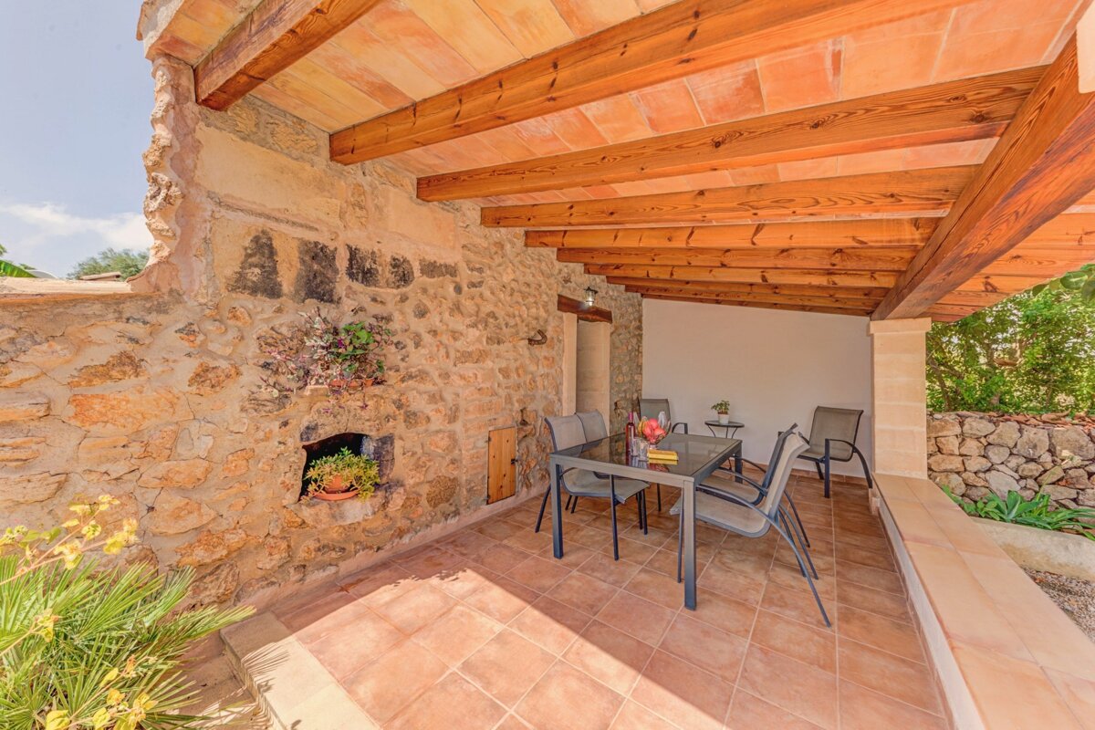 A patio with a table and chairs under a wooden roof