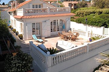 A white house with a balcony and a table and chairs