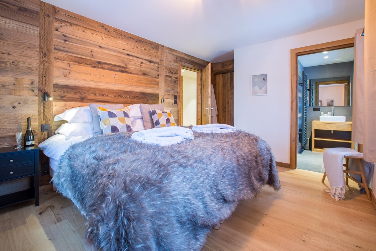 A bedroom with a bed and a nightstand with a bottle of wine on it