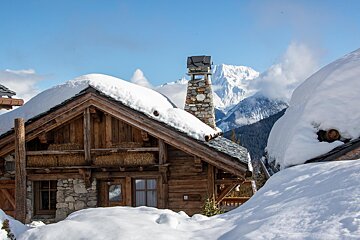 A snowy cabin with mountains in the background