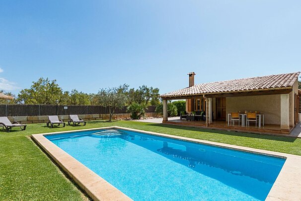 A house with a large swimming pool in front of it