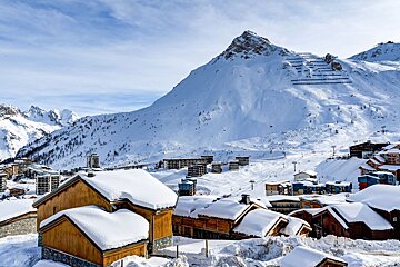 Snow covered buildings in a ski resort with a mountain in the background