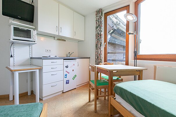 A room with a table and chairs and a refrigerator with stickers on it
